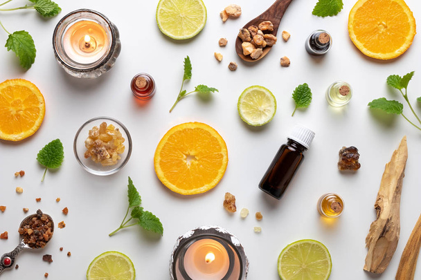 Bottles of essential oil with fresh citrus fruit, melissa, myrrh, white sandalwood and other ingredients - Zdjęcie, obraz