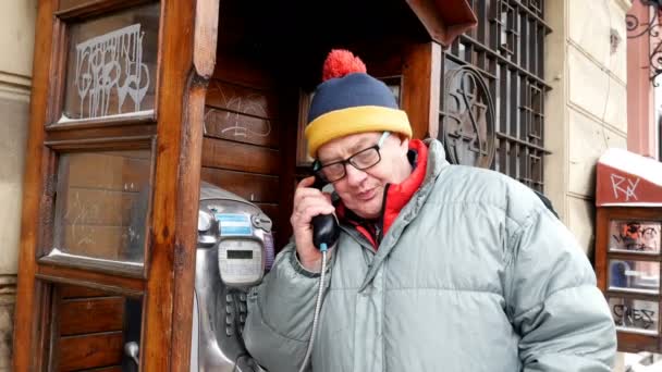 Automat telefoniczny call. Dorosły człowiek emocjonalnie mówiąc na telefon w publicznych automatów telefonicznych na ulicy. - Materiał filmowy, wideo