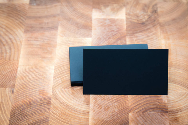 Photo of black blank business cards on wooden background. Template for ID. Top view - Foto, imagen