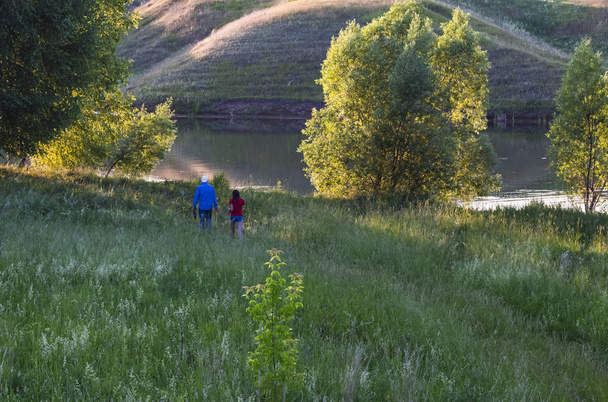 homme et fille marchant sur la rive verte du lac
 - Photo, image