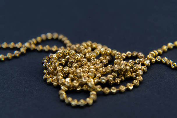 Gold necklace isolated on black background, macro closeup showing yellow golden chain links detail - Foto, Imagem