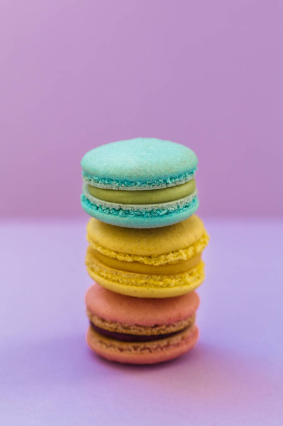 Sweet colorful French macaroon biscuits on violet purple background, top view. Flay lay selection of colorful macarons. - Foto, immagini