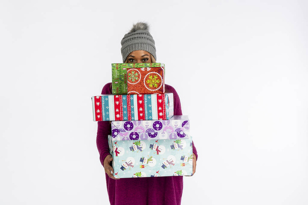 A gorgeous African American model posing with Christmas gifts against a white background in a studio environment - Photo, Image