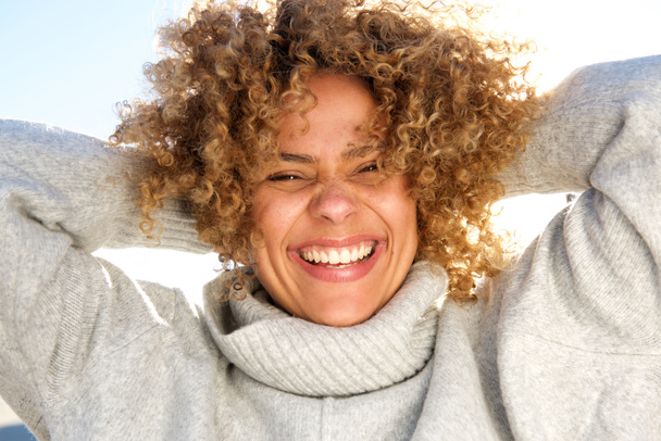 Retrato de cerca de la feliz mujer afroamericana riendo con las manos detrás de la cabeza
 - Foto, Imagen