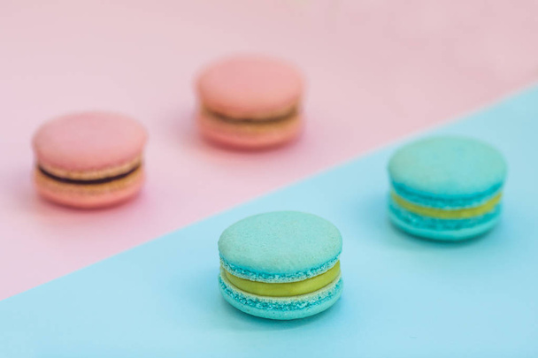 Sweet colorful French macaroon biscuits on pink and blue pastel background, top view. Flay lay selection of macarons. - Fotografie, Obrázek