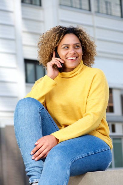 Porträt einer attraktiven jungen afrikanisch-amerikanischen Frau, die in der Stadt mit dem Handy spricht - Foto, Bild