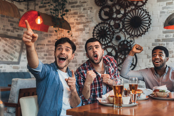 Мужчины фанаты кричат и смотрят футбол в баре
 - Фото, изображение