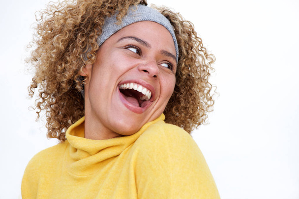 Nahaufnahme Porträt einer schönen afrikanisch-amerikanischen Frau, die lacht und sich vor isoliertem weißen Hintergrund über die Schulter dreht - Foto, Bild