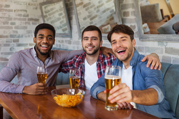 Men toasting with beer, sitting in bar - Foto, Bild
