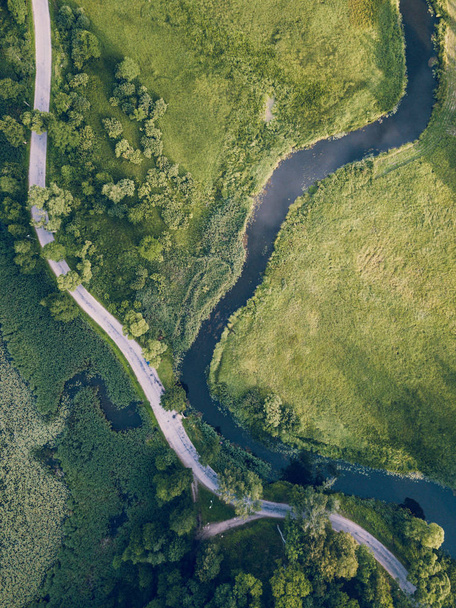 Аэрофотоснимок дороги, идущей по реке под деревьями, вид сверху вниз ранней весной в солнечный день - о мирной жизни в сельской местности в Феодосии, Винтажный киновзгляд
 - Фото, изображение