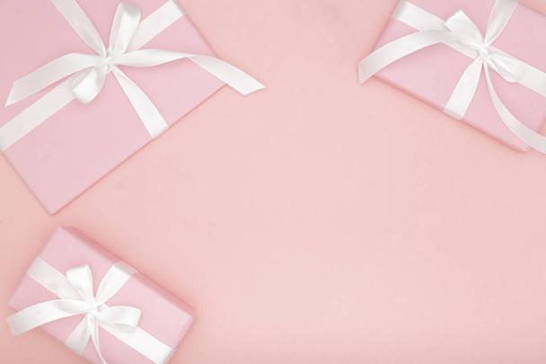 Dia dos namorados ou mulheres presente rosa com fita branca em fundo de papel de coral. Conceito decoração amor dia ou aniversário. Deitado. Espaço de cópia
 - Foto, Imagem