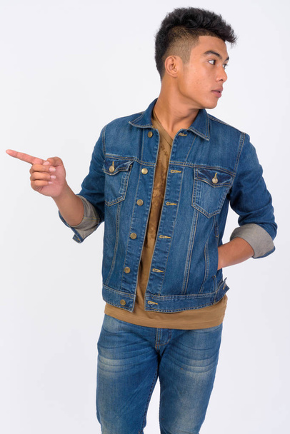 Young Asian man pointing to the side and looking away - Foto, Bild