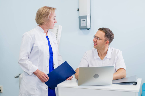 Arzt und Krankenschwester überprüfen Patientendaten auf einem Laptop im Büro - Foto, Bild