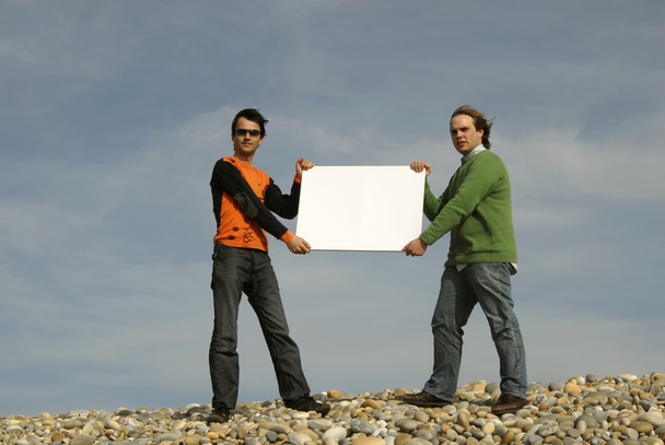 Two young men holding a white card - Photo, Image
