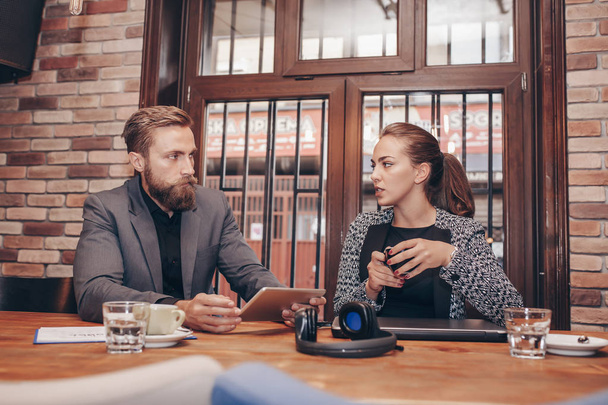 Бизнесмены обсуждают во время использования цифровых планшетов и питья кофе во время работы в кафе
 - Фото, изображение