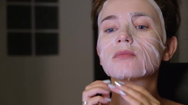 Young woman taking off sheet mask - Кадри, відео