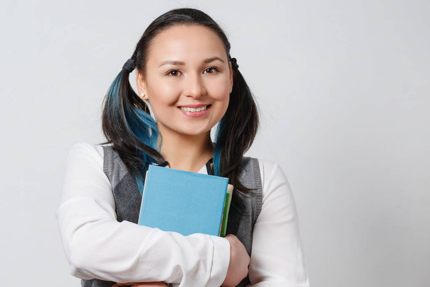 A pretty young girl is a student of a high school student with a stack of textbooks in her hands in front of her. on white background - Foto, Bild