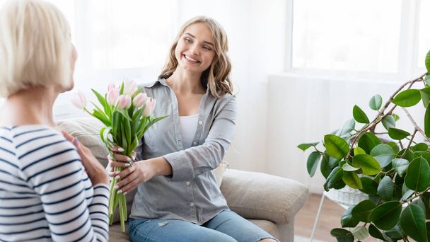Счастливая женщина дарит букет тюльпанов маме
 - Фото, изображение