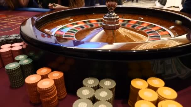 Closeup shot of casino roulette spinning around with casino chips put in piles near. Hands of urecognizable people holding cards and chips, people gambling. Casino concept. hd - Footage, Video
