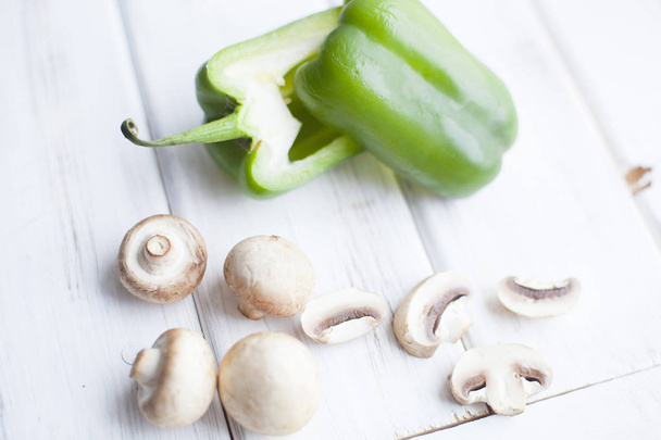 Healthy Food, Vegetarian Concept. A sweet green pepper cut in halves and champignones on a white wooden background with copy space, top view - Fotó, kép