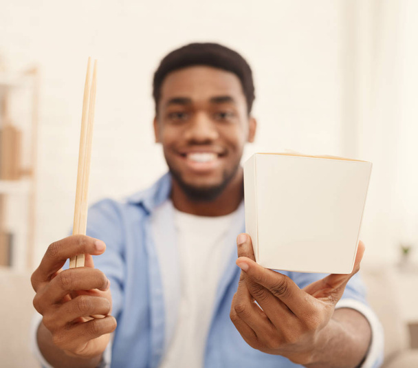 Excited black man showing delivery box and chopsticks - Photo, Image