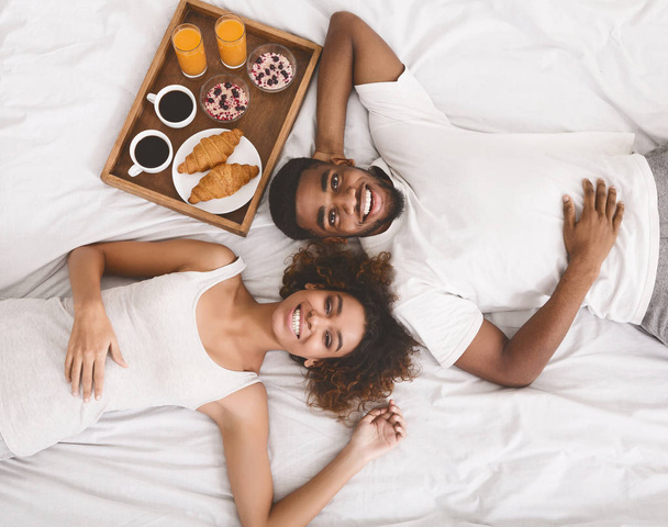 Happy young couple eating breakfast in bed in morning - Foto, Imagem