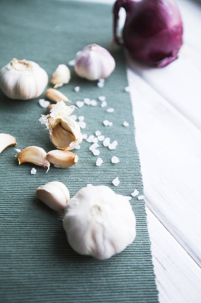 Flavour for any Meal. Red onion, garlic bulbs and garlic cloves, blue linen napkin and white wood as a background, - Fotó, kép