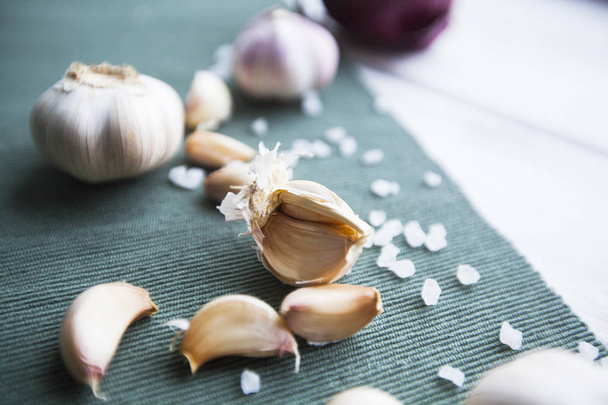 Flavour for any Meal. Red onion, garlic bulbs and garlic cloves, blue linen napkin and white wood as a background, - Fotografie, Obrázek