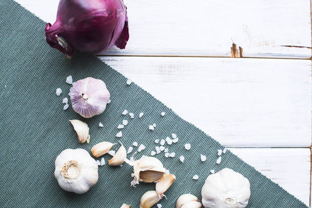 Flavour for any Meal. Red onion, garlic bulbs and garlic cloves, blue linen napkin and white wood as a background, - Foto, Imagem