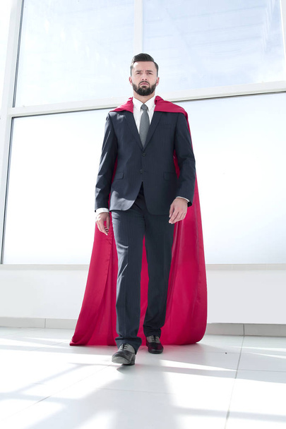 businessman in a Superman cloak standing in a bright office - Fotoğraf, Görsel