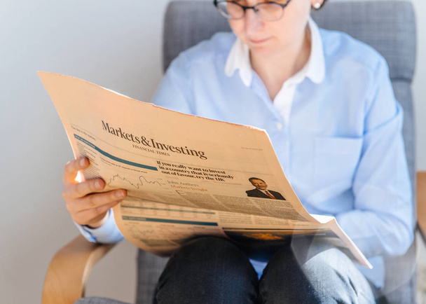 Nő olvasó pénzügyi alkalommal újságot hivatalban - Fotó, kép