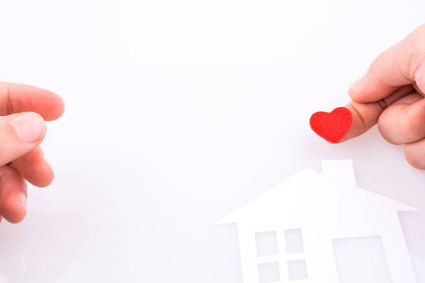 Паперовий будинок і форма серця в руці на білому тлі
 - Фото, зображення