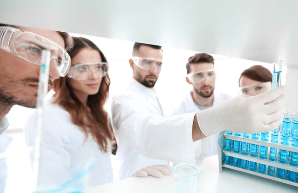 background image is a group of microbiologists studying the liquid in the glass tube. - Foto, Imagem