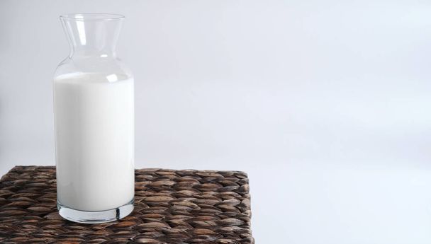 Il latte in una bottiglia di vetro sta su una scatola di vimini
                                - Foto, immagini