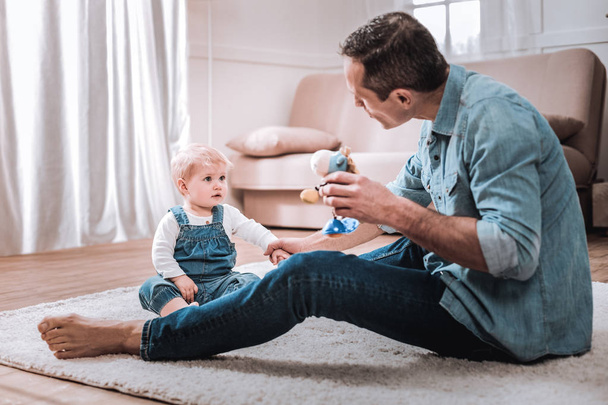 Positive joyful man showing a toy to his child - Photo, image