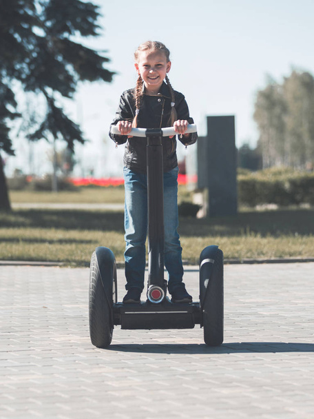 portrait of a little girl riding an electric mini hoverboard in the Park. - Foto, Imagen