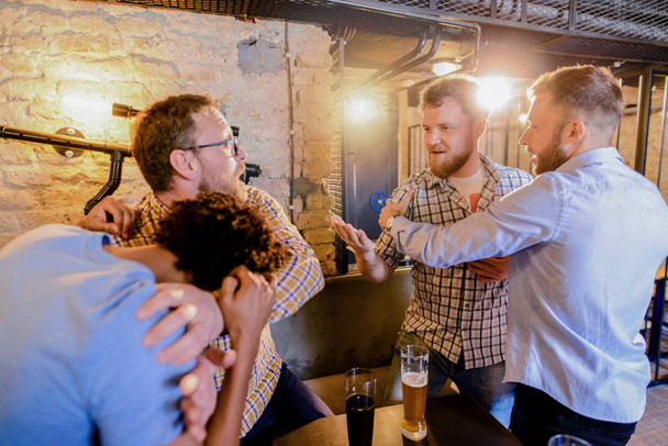 friends preventing fighting of two angry guys in the bar - Photo, image
