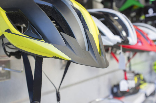 Nuevos cascos de bicicleta exhibidos en la tienda. Pintado con color reflectante altamente visible
 - Foto, imagen