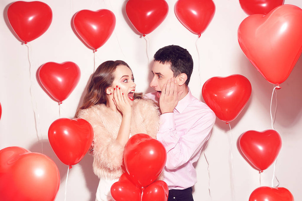 Sevgili sevgilisiyle birlikte olan adam şok oldu. Sevgililer Günü 'nde. Sevgililer Günü. Çift şaşırdı, çok mutlu, indirimler, indirim, parti, gülümseme, kahkaha. Arka plan kırmızı balonlar kalpler. Aşk konsepti - Fotoğraf, Görsel
