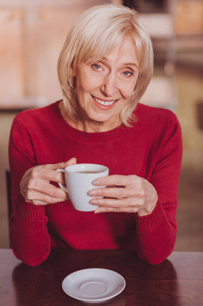Delighted woman having coffee and relaxing - Photo, Image