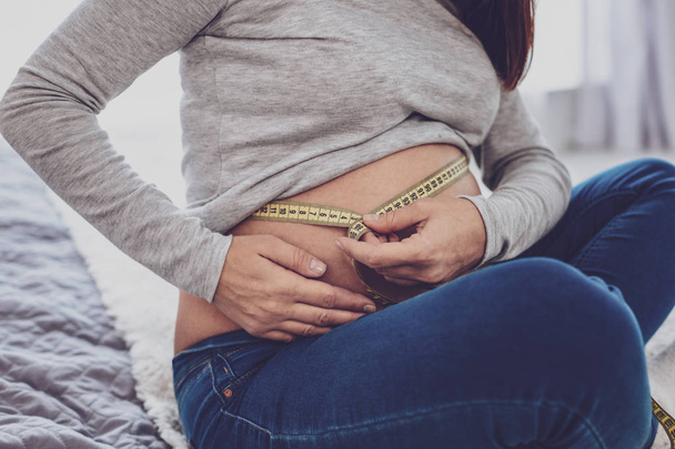 Close up of pregnant woman measuring belly - Fotografie, Obrázek