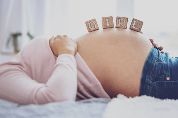 Pregnant woman holding bricks saying Girl on belly - Photo, Image
