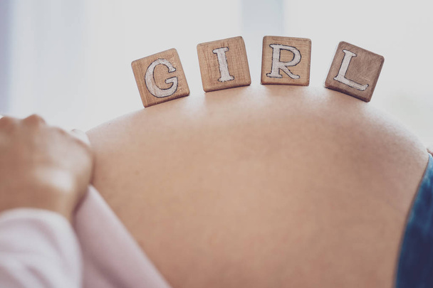 Close up of bricks saying Girl on pregnant womans belly - Фото, зображення