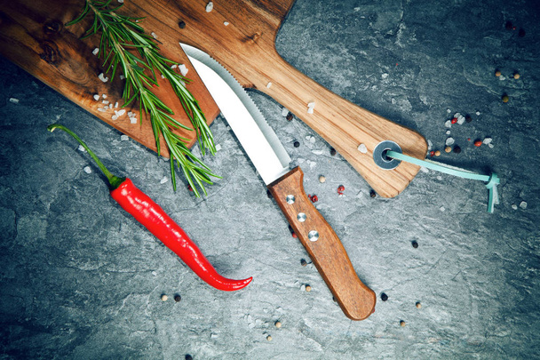 Red hot chilli pepper, spices, knife and wooden board on grey table - Foto, Bild