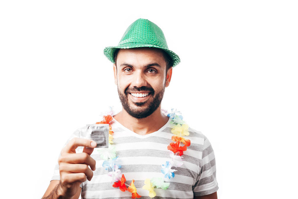 Portrait of young brazilian man wearing carnival costume showing a condom - Foto, Imagen