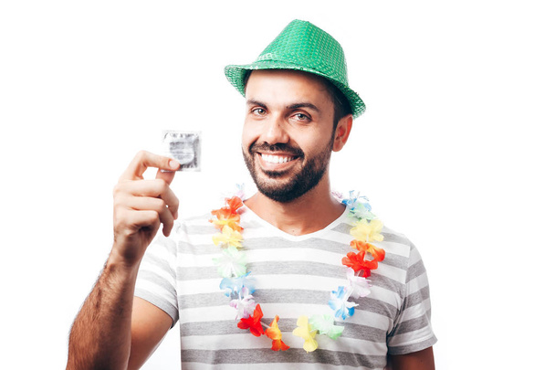 Portrait of young brazilian man wearing carnival costume showing a condom - Φωτογραφία, εικόνα