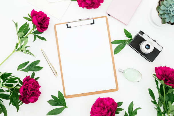 Workspace with diary, retro camera, peonies flowers, clipboard, coffee cup and accessories on white background. Flat lay, top view. - Foto, Bild