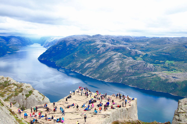 Varios excursionistas disfrutan de las vistas en la cima de la Roca del Púlpito (Preikestolen), uno de los miradores más espectaculares del mundo. Una meseta que se eleva 604 metros por encima del Lysefjord, Noruega
. - Foto, Imagen