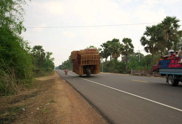 Kampong Thom, Cambodia-January 12, 2019: A motorcycle runs on National Highway 6 in Cambodia loading lots of rattan boxes - Foto, afbeelding