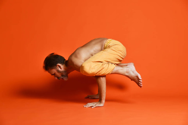 Sporty old beard man working out, doing handstand yoga asana, Crane (Crow) Pose - Foto, afbeelding